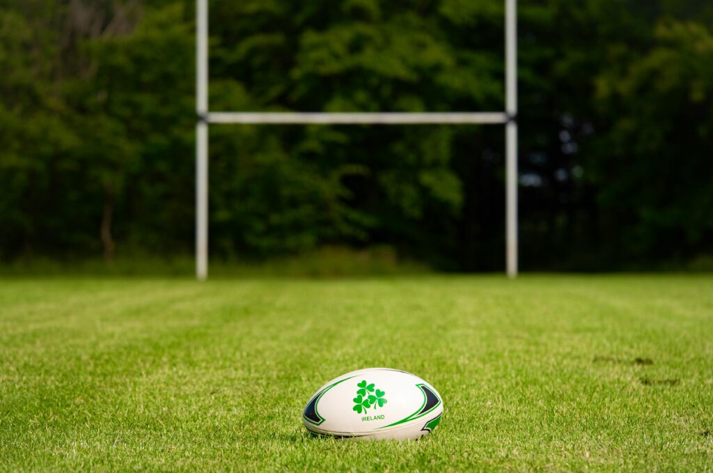 Rugby ball on a grassy field with goal posts in the background, Galway, Ireland.