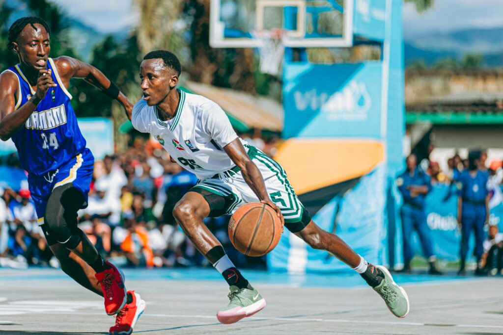 Two players in a competitive basketball game on an outdoor court during the day.