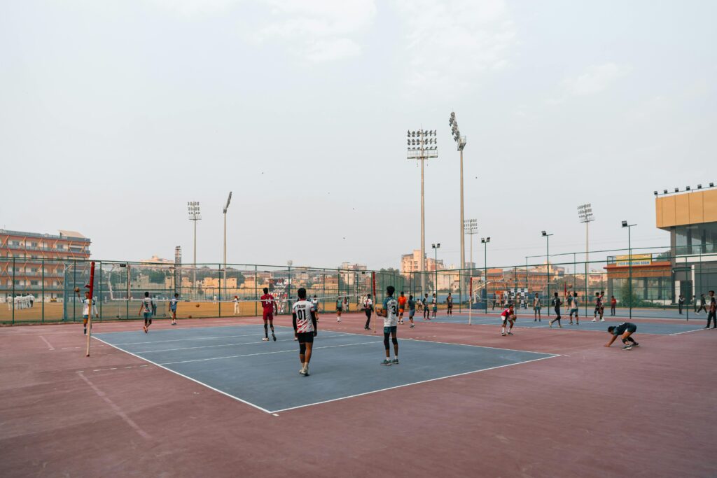 Players engaged in a volleyball match on an outdoor court in a cityscape.