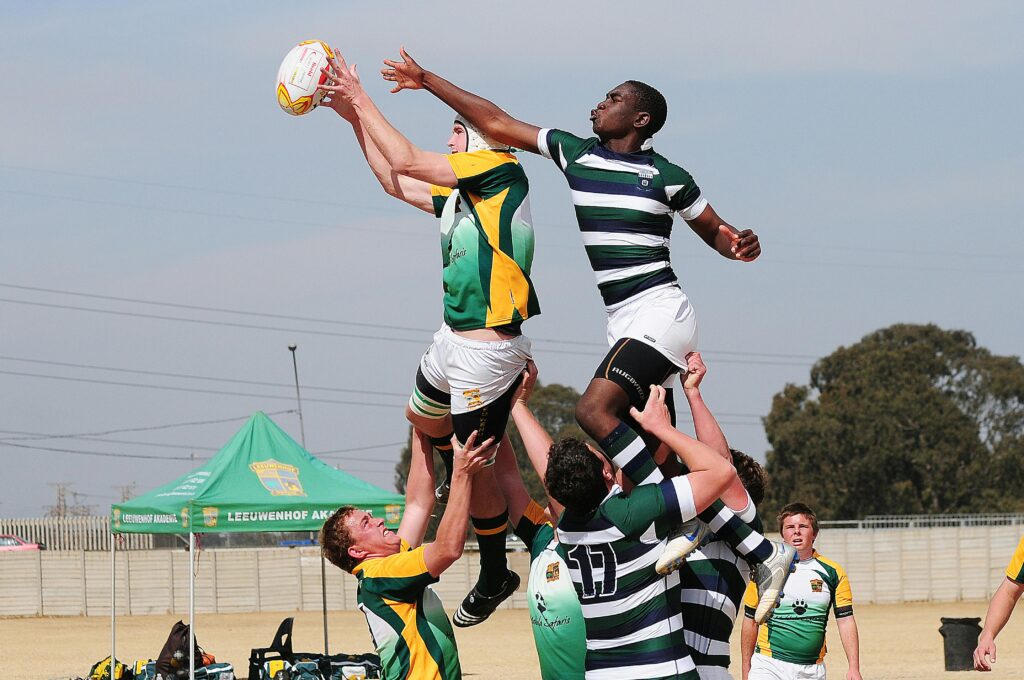 Energetic rugby players leap for the ball during a competitive match, showcasing teamwork and athleticism.